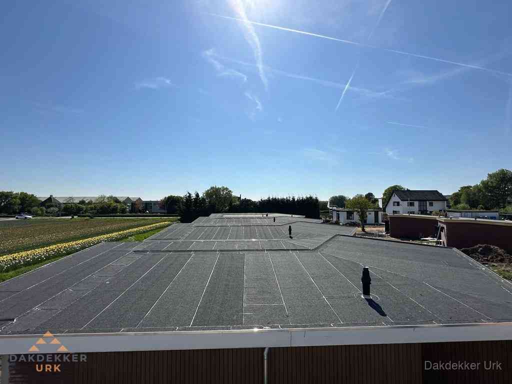 Groot plat dak met bitumen dakbedekking op bedrijfspand in Urk