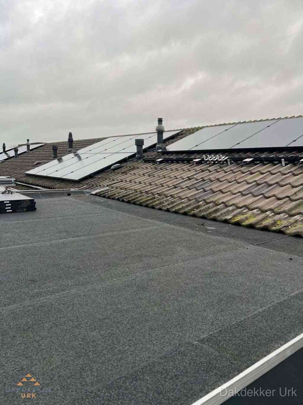 Plat dak inspectie met bitumen bedekking naast schuin pannendak in Urk