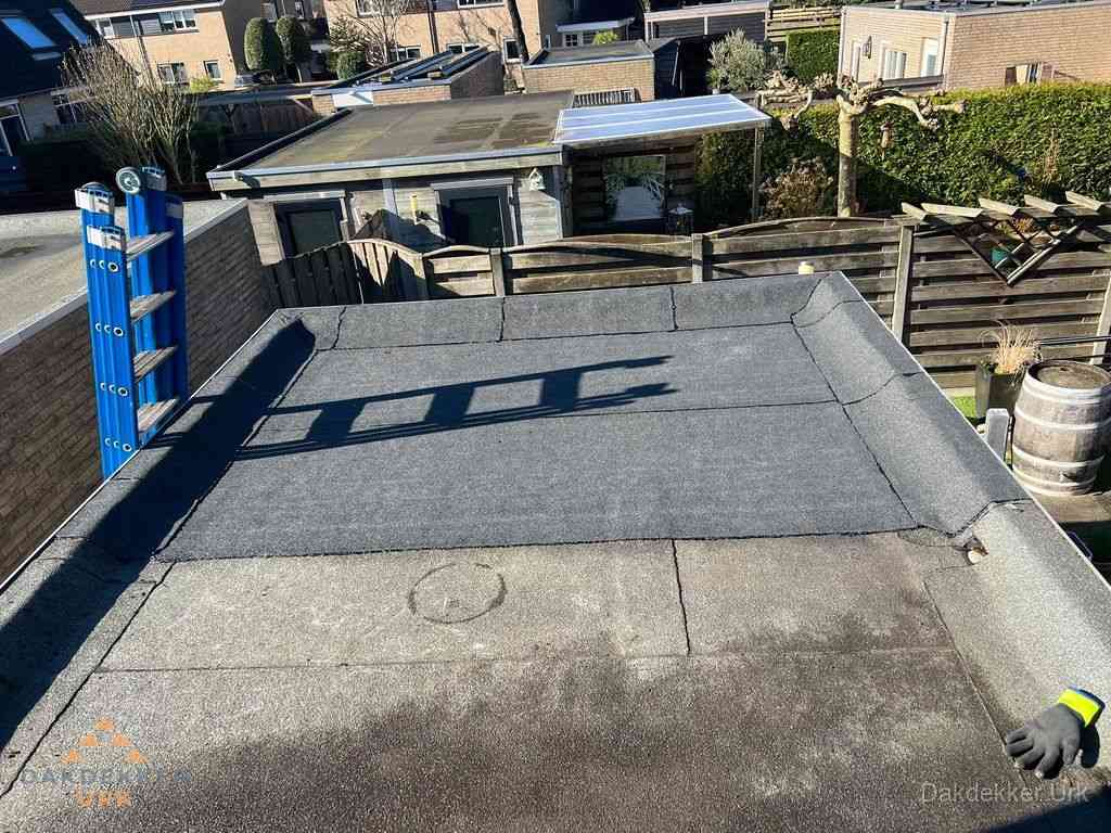 Dakdekker legt onderlaag op plat dak met houten constructie in Urk