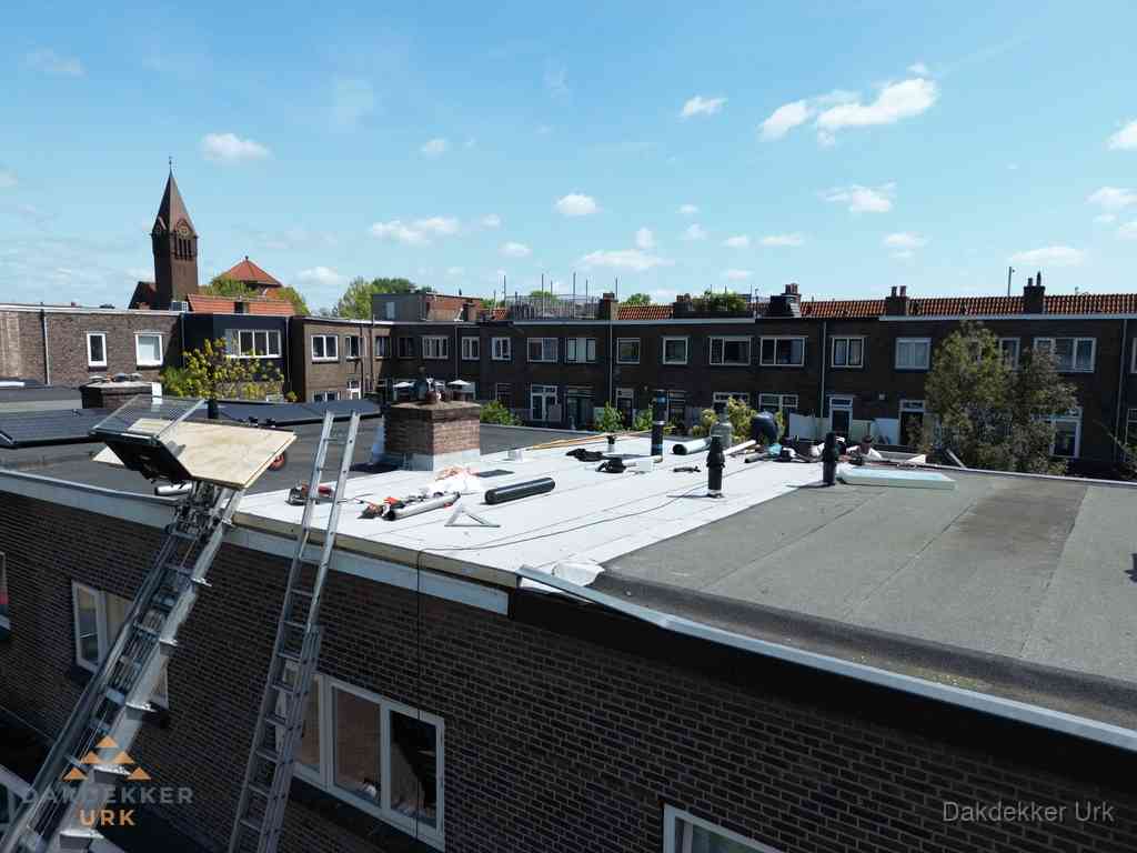 Dakdekkers aan het werk op plat dak in Urk