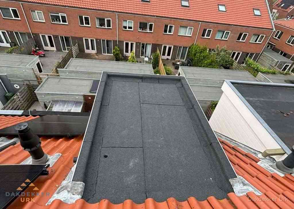 Plat dak met bitumen bedekking naast dakkapel in Urk