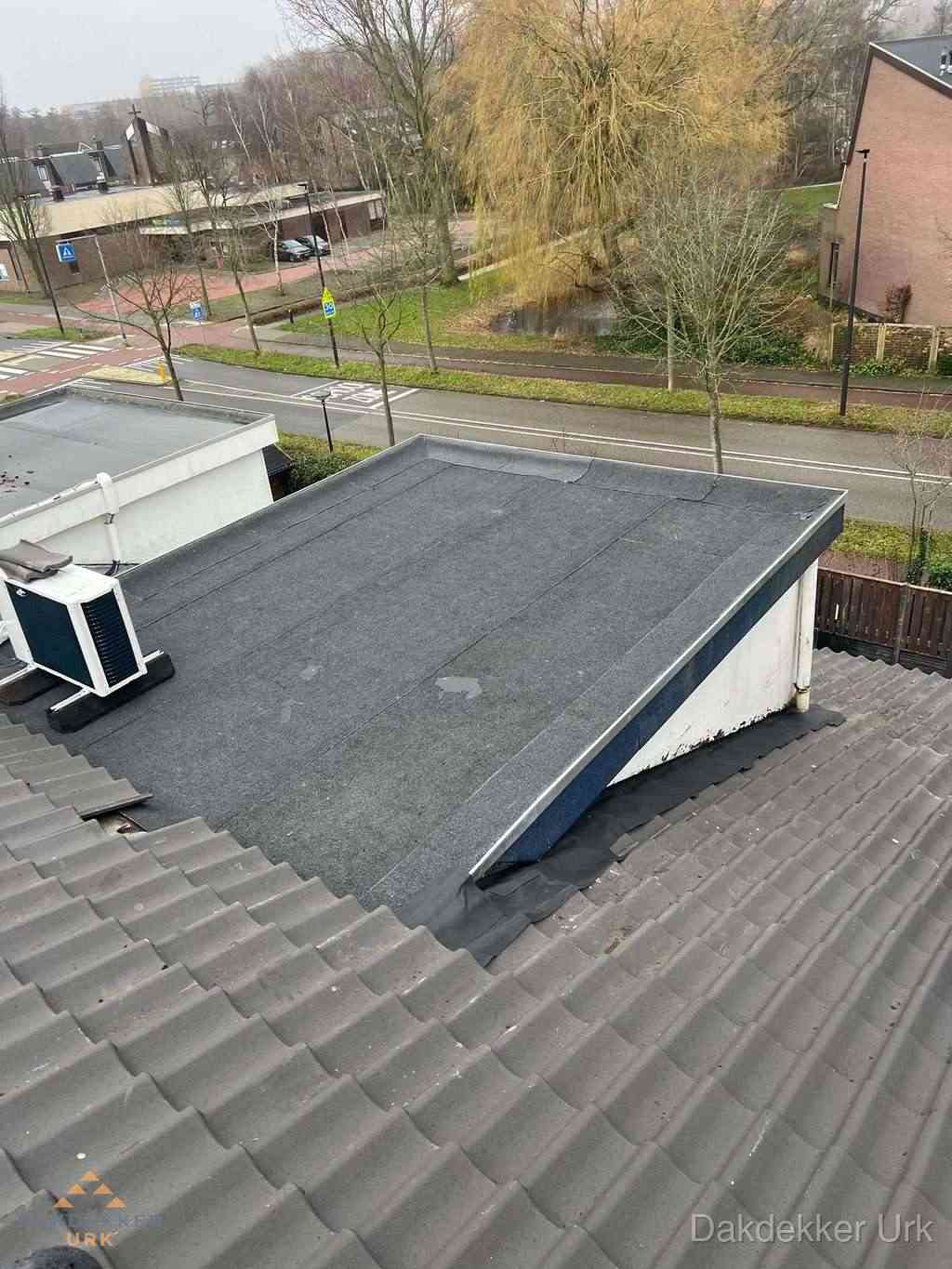 Plat dak met bitumen dakbedekking naast schuin pannendak in Urk