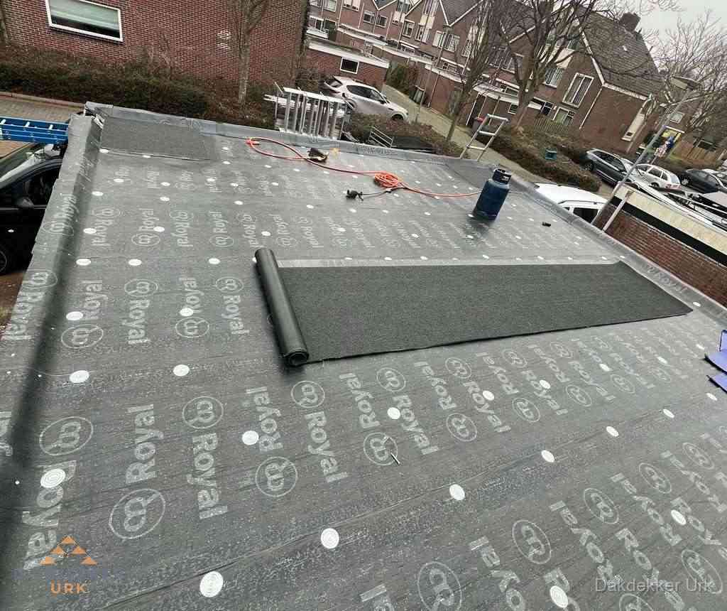 Dakdekker aan het werk met gasbrander op plat bitumen dak in Urk
